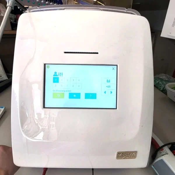 A front view of a white Apilus xCell Pur electrolysis device with its digital touchscreen display turned on, showing a settings and profile selection menu.